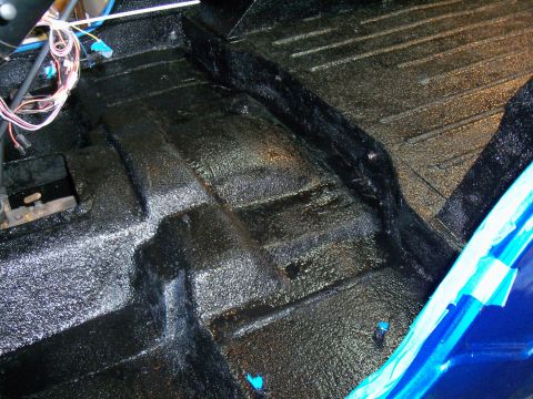 1978 Jeep CJ5 - The interior floor of a vehicle shows a textured black coating and exposed wiring.