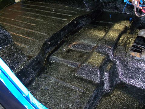 1978 Jeep CJ5 - Vehicle interior floor pan coated with black textured material, revealing ribbed sections and a central tunnel.