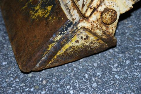 1979 Ford Bronco - Close-up view of a heavily rusted bucket, showing signs of wear and yellow paint.