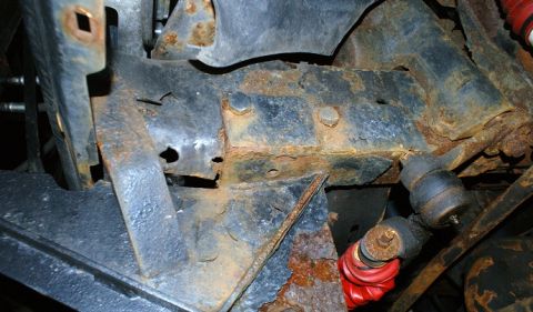 1979 Ford Bronco - Close-up view of heavily rusted frame and suspension components, with a red shock absorber in view.