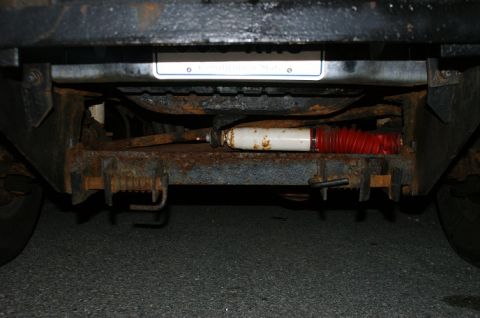 1979 Ford Bronco - The rear suspension and frame of a vehicle are visible, showing signs of rust and wear.