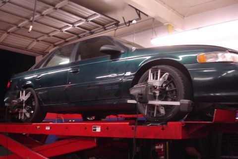 1995 Ford Taurus - A green 1995 Ford Taurus is positioned on a car lift for wheel alignment service.