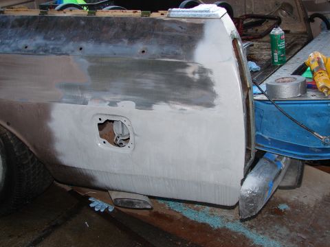 1973 Ford Ranchero - The rear quarter panel of a vehicle is shown with body filler applied and the gas cap opening exposed, indicating ongoing repair work.