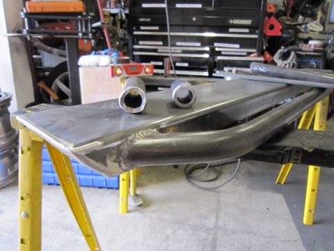 1996 Ford Bronco - Metal fabrication parts, including bent tubing and pipe sections, are laid out on sawhorses in a workshop.