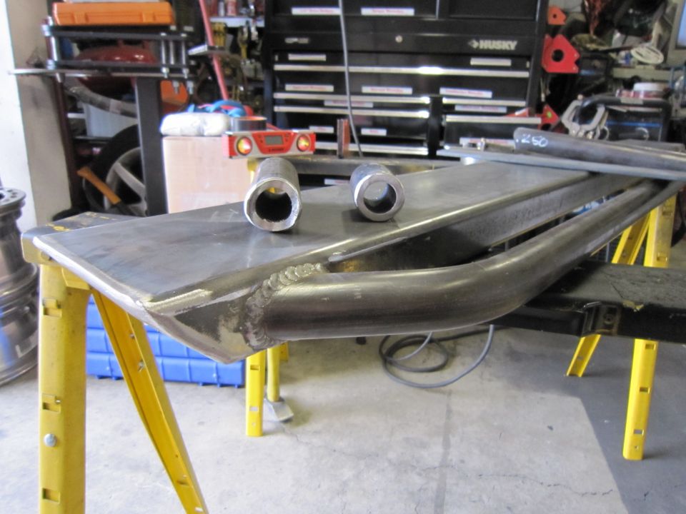 Metal fabrication parts on sawhorses, with two pipe sections and a level