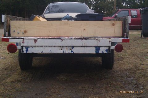 2000 Mercury Grand Marquis - A trailer is loaded with items, and a car is parked behind it.