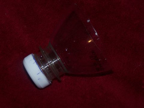 1986 Ford Bronco - The cut-off top of a clear plastic bottle with its white screw cap still attached, lying on dark red carpet, apparently repurposed as a sho…