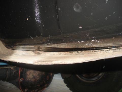 1986 Ford Bronco - Close-up view of a vehicle's undercarriage, revealing mechanical components and tire tread.