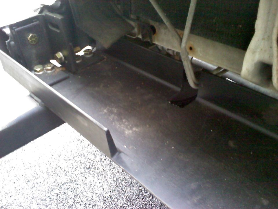 Underside view of black front bumper mount with bolts below a radiator on a 1996 Ford Bronco