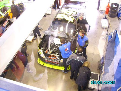 1978 Ford Bronco - Pit crew members attend to a race car in the garage, with another car visible in the background.