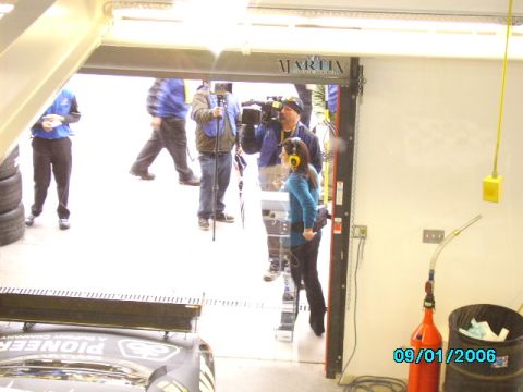 1978 Ford Bronco - A race car is visible in a garage setting with crew members and media present.