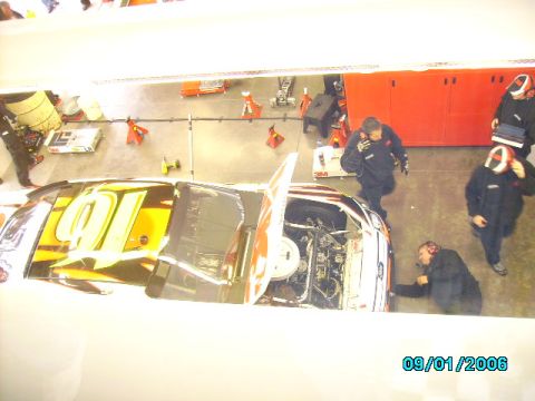 1978 Ford Bronco - Crew members attend to a race car in a garage, with the engine exposed.