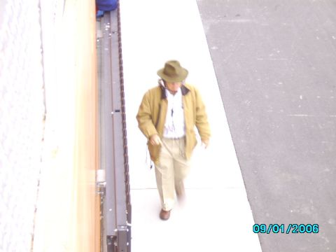 1978 Ford Bronco - A man wearing a hat and tan jacket walks on a sidewalk next to a building. The date 09/01/2006 is visible.