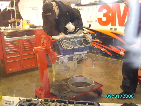 1978 Ford Bronco - Mechanics work on an engine block in a garage with a large 3M logo visible on the wall.