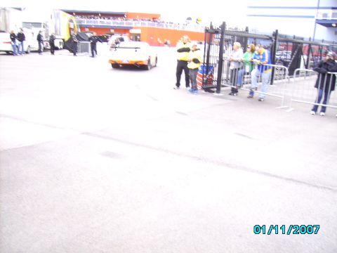 1978 Ford Bronco - A race car is on the track with spectators watching from behind a fence.