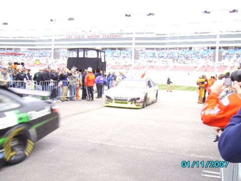 1978 Ford Bronco - Race cars are on the track at Las Vegas Motor Speedway, with spectators in the stands and along the fence.