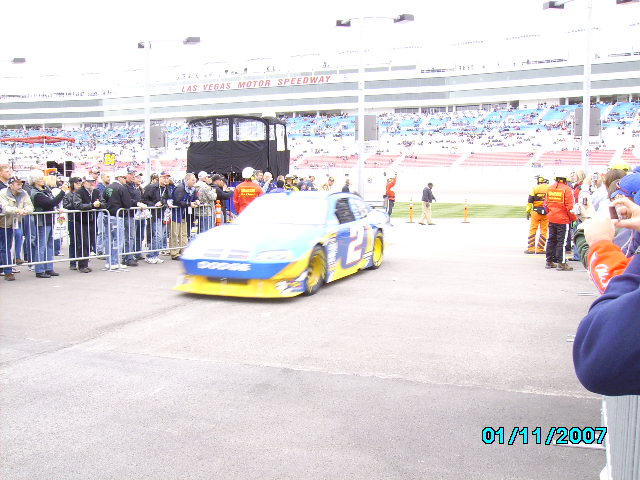 Race car with Dodge branding and number 2 on the side, driving past spectators at Las Vegas Motor Speedway