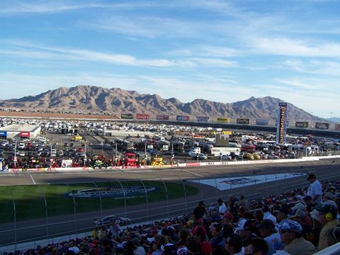 1978 Ford Bronco - A wide view of a busy race track with spectators in the foreground and a vast parking area beyond.