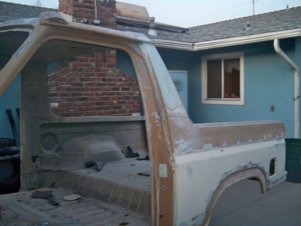 Body of a 1980s Ford Bronco, stripped down and prepped for paint. Interior is empty, showing the floor pan and seat mounts