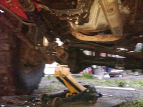 1978 Ford Bronco - Undercarriage view of a vehicle being supported by a floor jack, with suspension parts visible.
