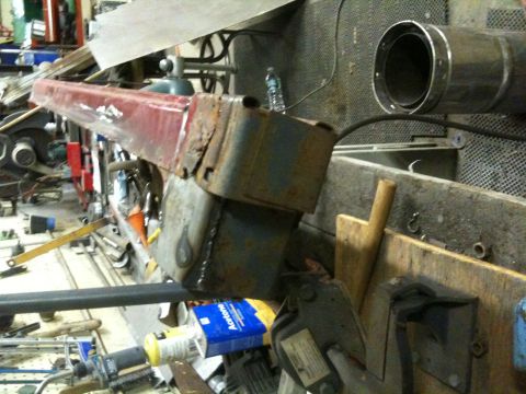 1993 Ford Bronco - A close-up shows a heavily rusted red metal component, possibly a vehicle frame section, in a workshop setting.