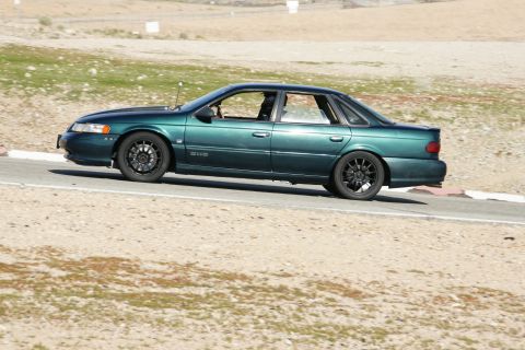 1995 Ford Taurus - A green 1995 Ford Taurus SHO is seen on a race track, likely during a track day event.