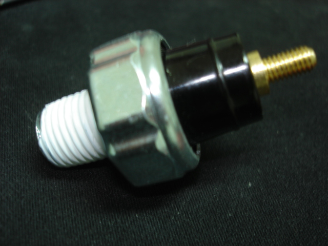 Oil pressure sensor with metal hex fitting and black plastic body, threaded end with white sealant