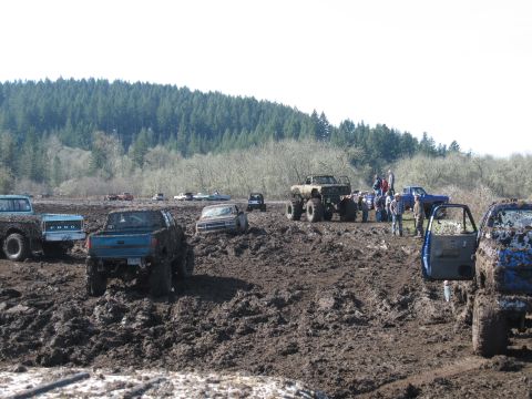 1996 Ford Bronco - Multiple trucks are stuck in the mud at an outdoor event.