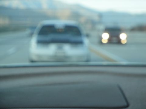 1995 Ford Taurus - Two cars drive on a highway, one in front of the other, with mountains in the background.