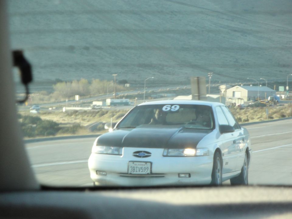 White 1995 Ford Taurus with black hood and racing number 69 on windshield