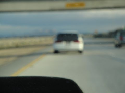 1995 Ford Taurus - A white sedan is seen from behind on a highway, with another vehicle in the adjacent lane.