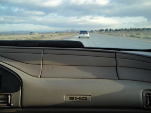 1995 Ford Taurus - Interior view of a 1995 Ford Taurus SHO driving on a highway, with another vehicle in the distance.
