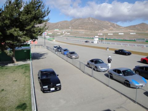 1995 Ford Taurus - Cars gathered at a race track with mountains visible in the distance under a cloudy sky.