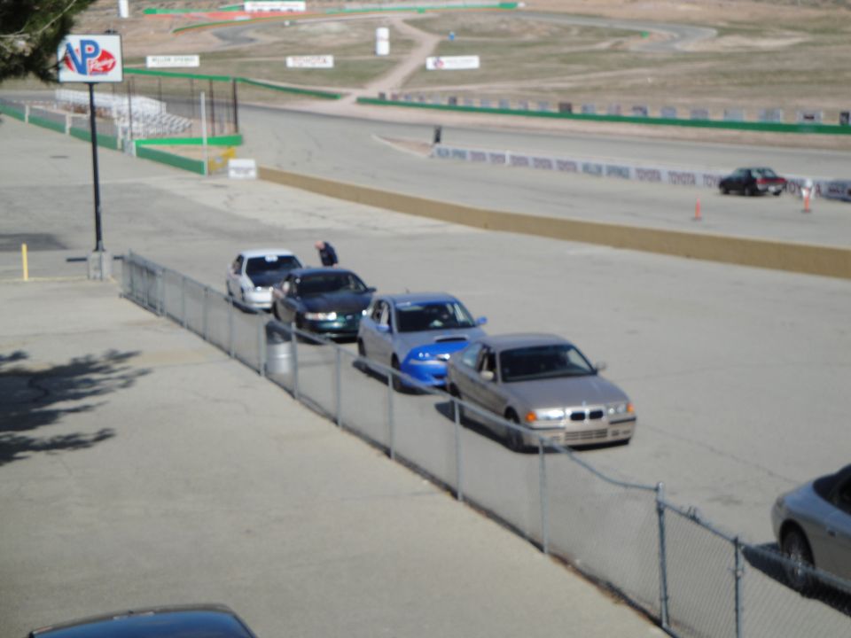 Silver sedan in a line of cars on a racetrack