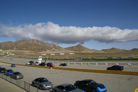 1995 Ford Taurus - A scenic view of a racetrack with multiple vehicles and distant mountains under a partly cloudy sky.