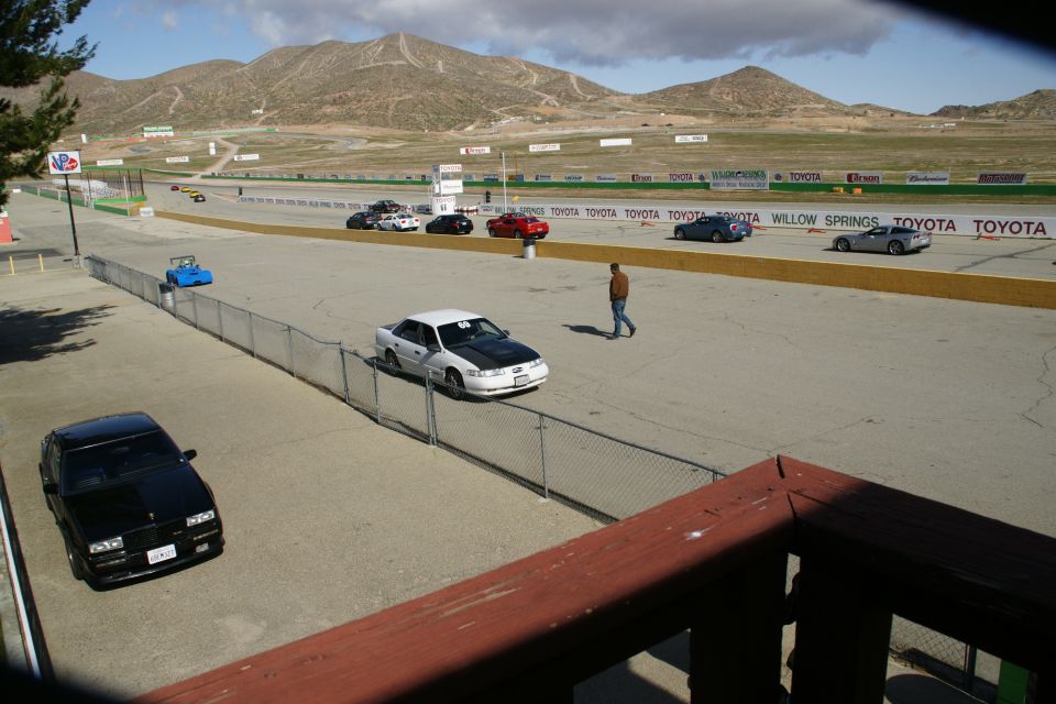 Race track with several cars on the asphalt, mountains in the distance
