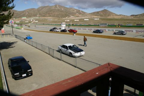 1995 Ford Taurus - A sunny day at Willow Springs International Raceway with several cars on the track and surrounding areas.