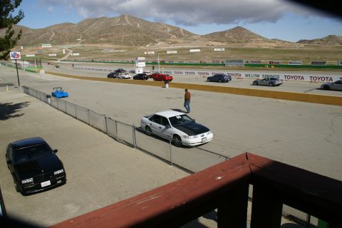 1995 Ford Taurus - Multiple vehicles are on a race track with mountains in the background.