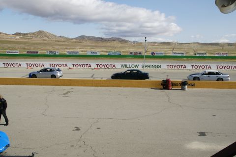1995 Ford Taurus - A trio of sedans are lined up on a racetrack, with prominent Toyota branding visible on the surrounding wall.