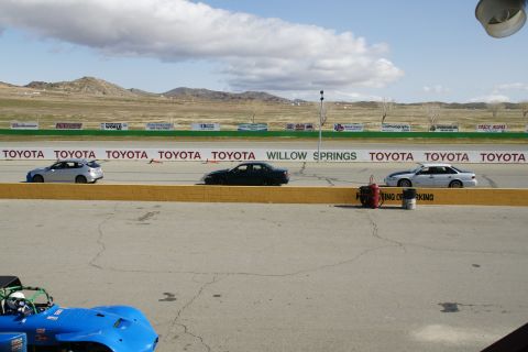 1995 Ford Taurus - A dark sedan drives on a race track with a Toyota sponsorship banner in the background.