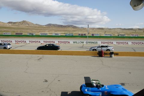 1995 Ford Taurus - Cars on a race track with mountains and banners in the background.