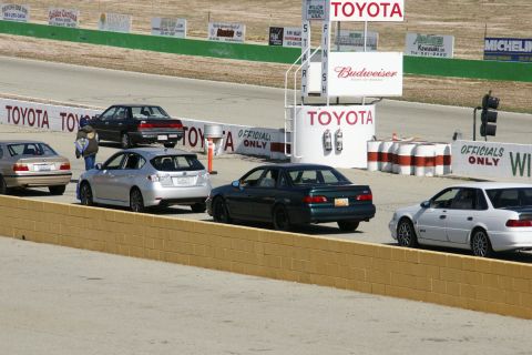 1995 Ford Taurus - Multiple vehicles line up on a race track, with prominent Toyota branding visible in the background.