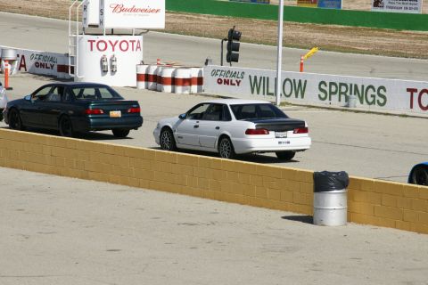 1995 Ford Taurus - Two sedans are on the Willow Springs race track, one white and one dark green.
