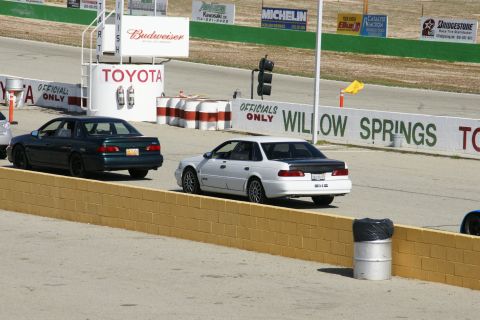 1995 Ford Taurus - Two sedans are on the race track at Willow Springs. The white car has a black trunk lid.