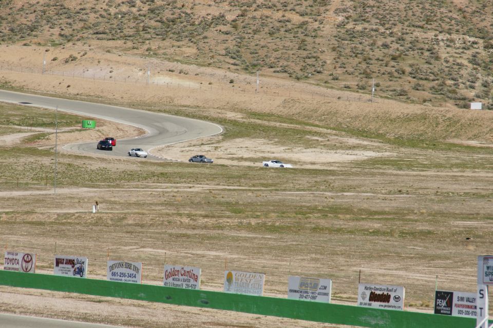 cars on a winding race track with dry hills in background
