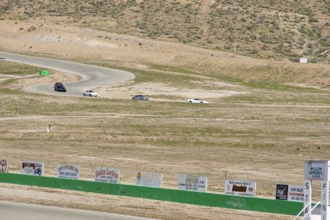 1995 Ford Taurus - Multiple vehicles are seen on a winding race track under a clear sky.