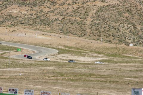 1995 Ford Taurus - Multiple vehicles compete on a race track surrounded by arid hills and sparse vegetation.