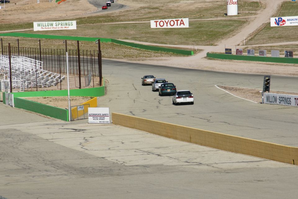 Cars on a race track with signs for Willow Springs and Toyota