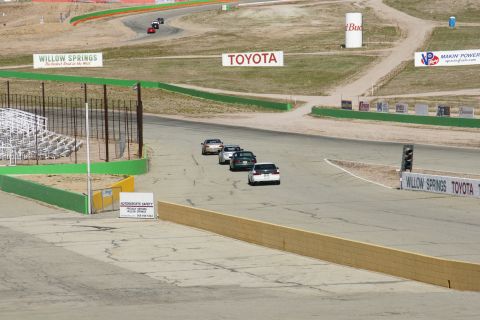 1995 Ford Taurus - Several cars are seen on a race track, with various sponsor signs visible in the background.