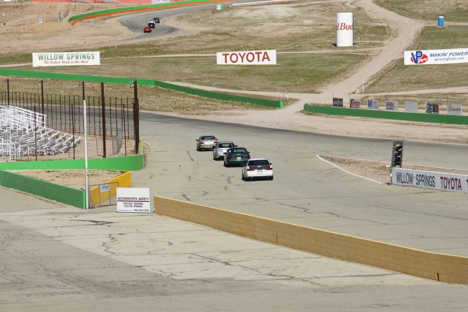 Cars driving on a race track with signs for Willow Springs and Toyota